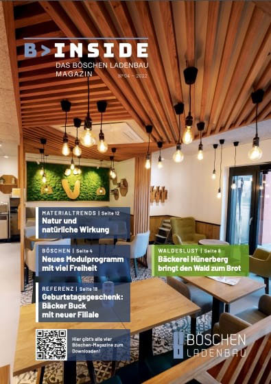 Titelbild der Ausgabe 1/2022 des Magazins „B>INSIDE – Das Böschen Ladenbau Magazin“, zeigt einen modern gestalteten Gastraum mit hölzerner Deckenstruktur, grüner Mooswand mit stilisiertem Smiley-Logo und stilvoller Beleuchtung.